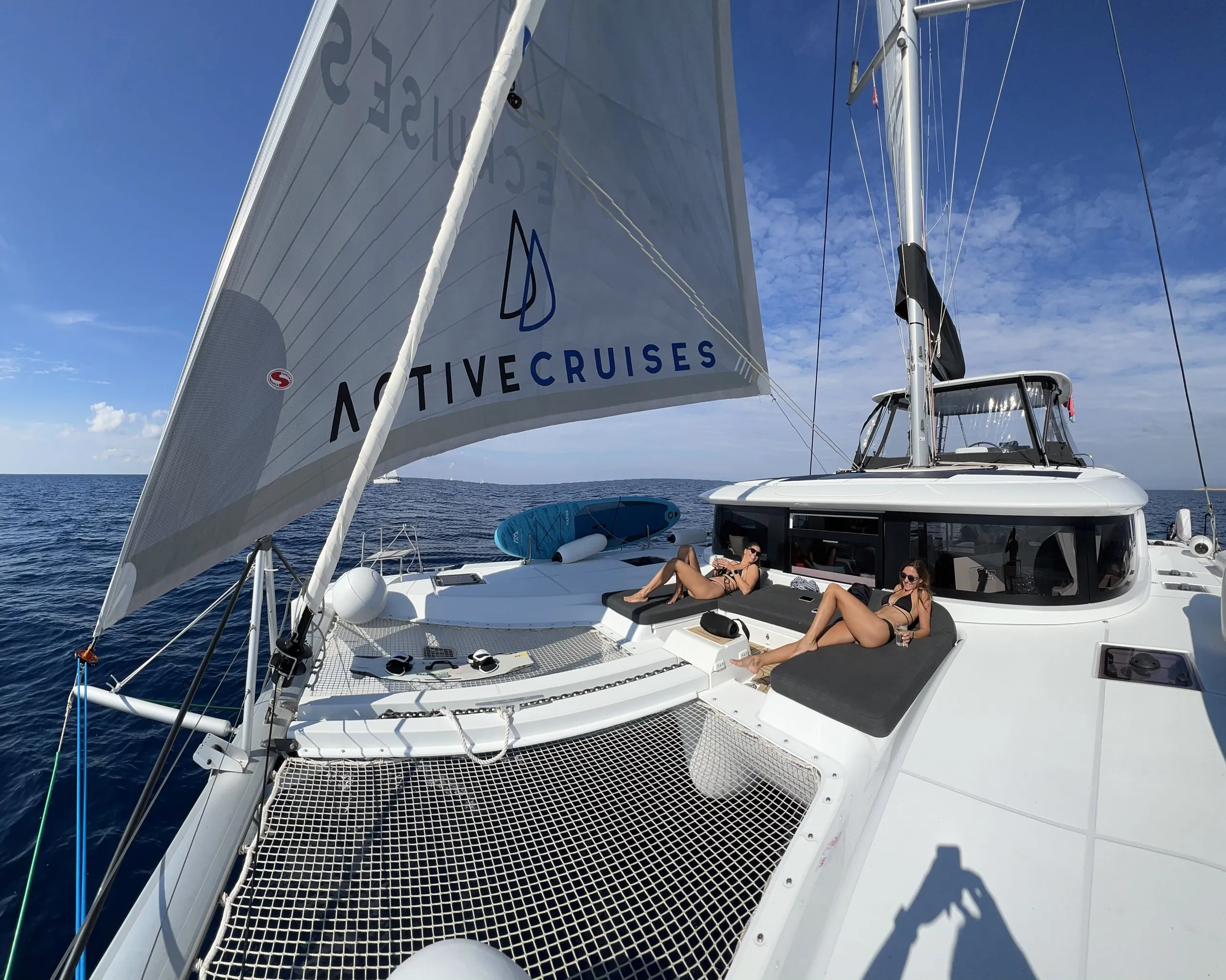 Guests lying on the bow cushions under the Active Cruises mainsail