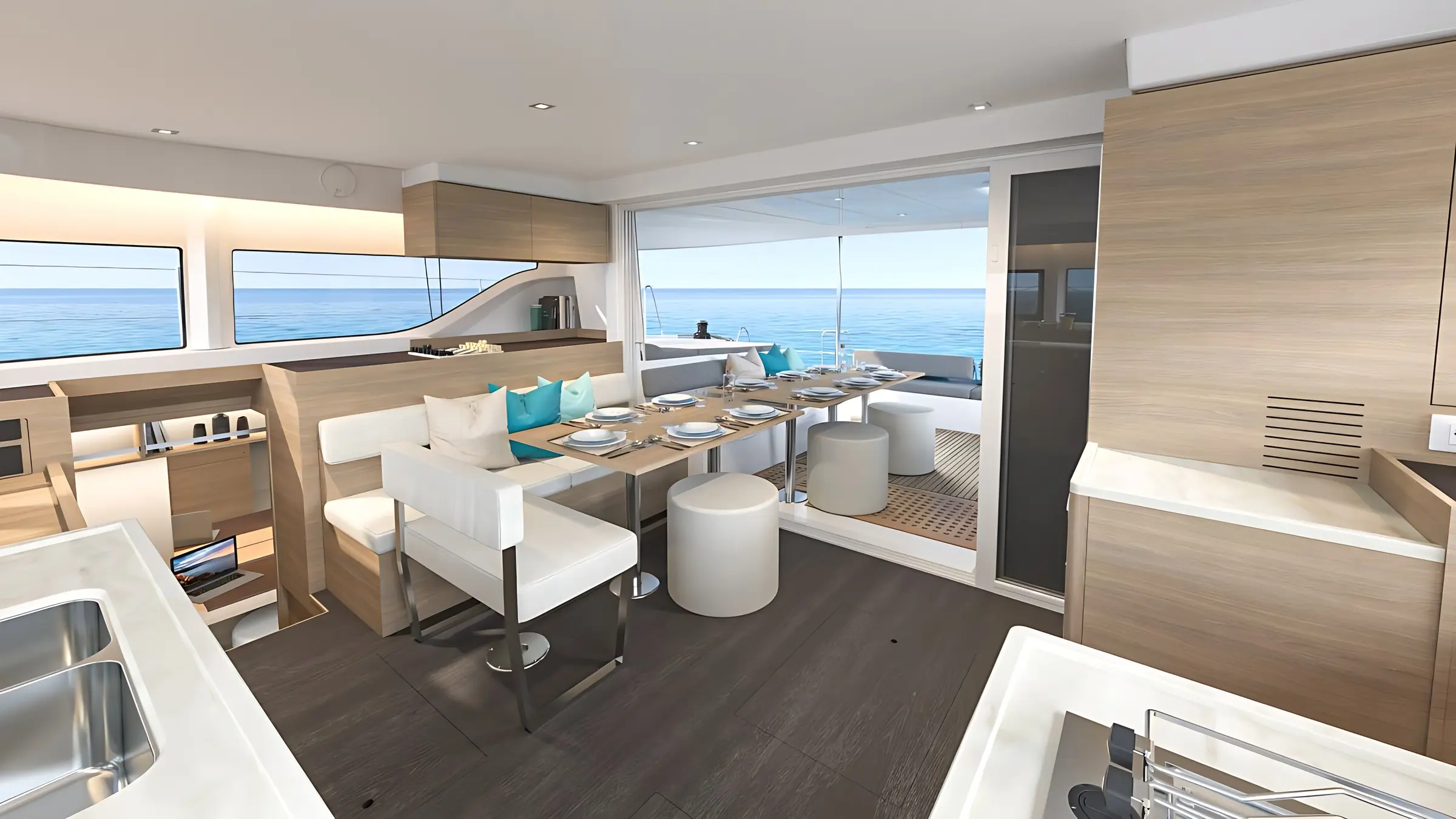 Modern Lagoon 43 yacht interior with a dining area set for six, neutral tones, large windows framing the sea, and a patio leading to outdoor seating. Light wood and white finishes create an airy, open atmosphere.